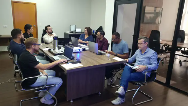 Reunião de liderança em volta de uma mesa, com notebooks abertos.